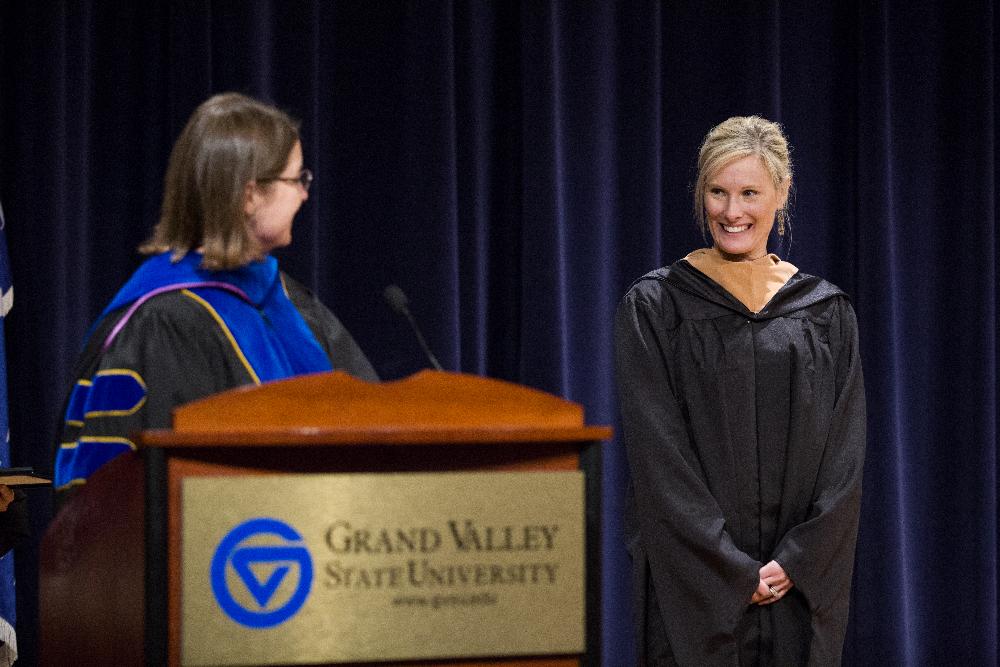 A faculty member smiles as she receives acknowledgment from event speaker